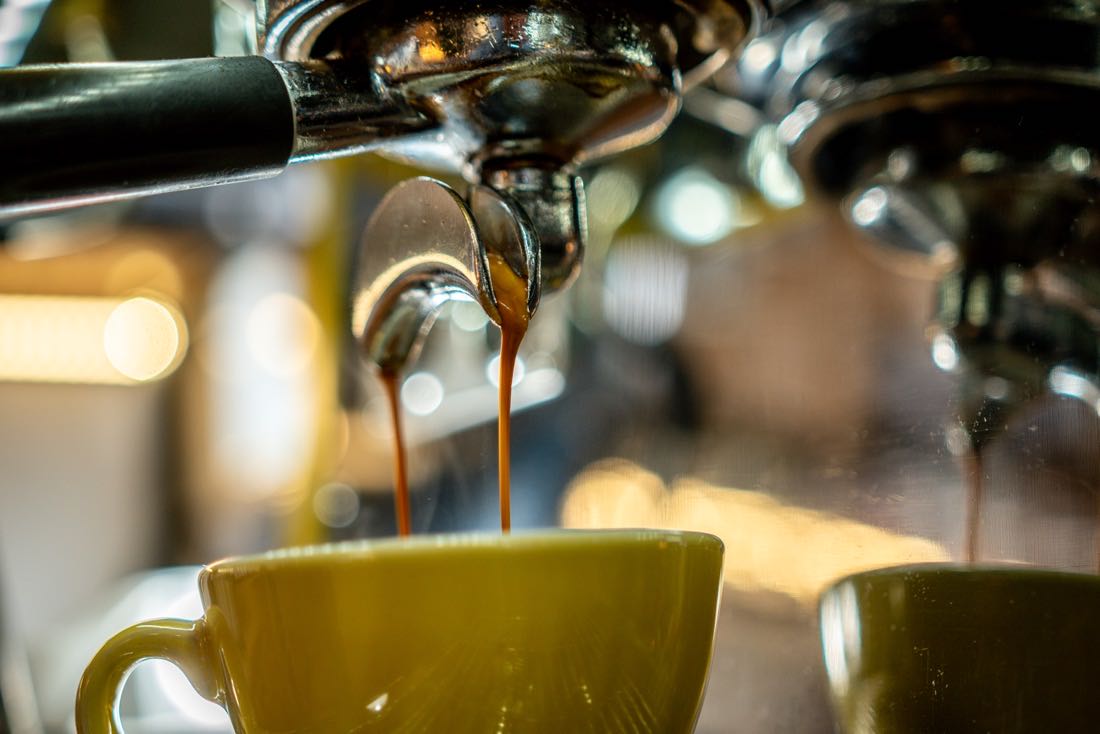 Espresso wypływające z kolby do żółtej filiżanki